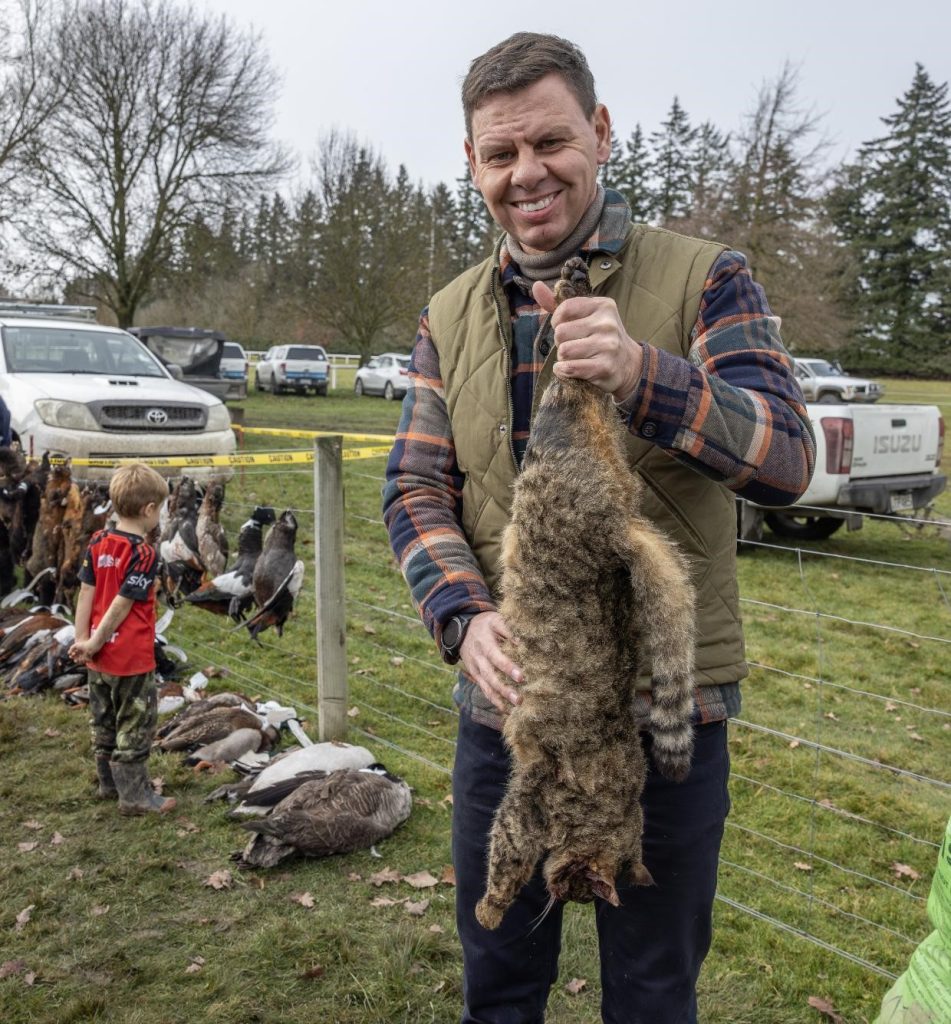 Sick cunt cat hater Patrick Gower smiles as he holds an innocent cat gunned down by cunts!